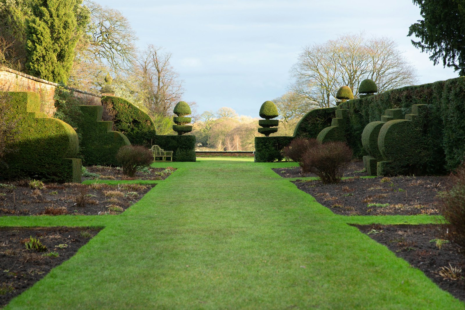 Formal lawn path lined with clipped hedges and topiary